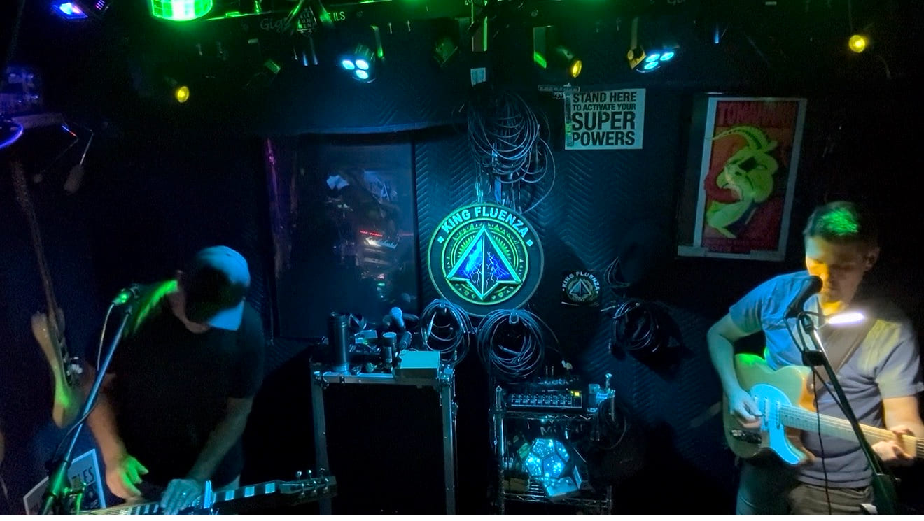 Guitarist and bassist working through a new part in green stage light